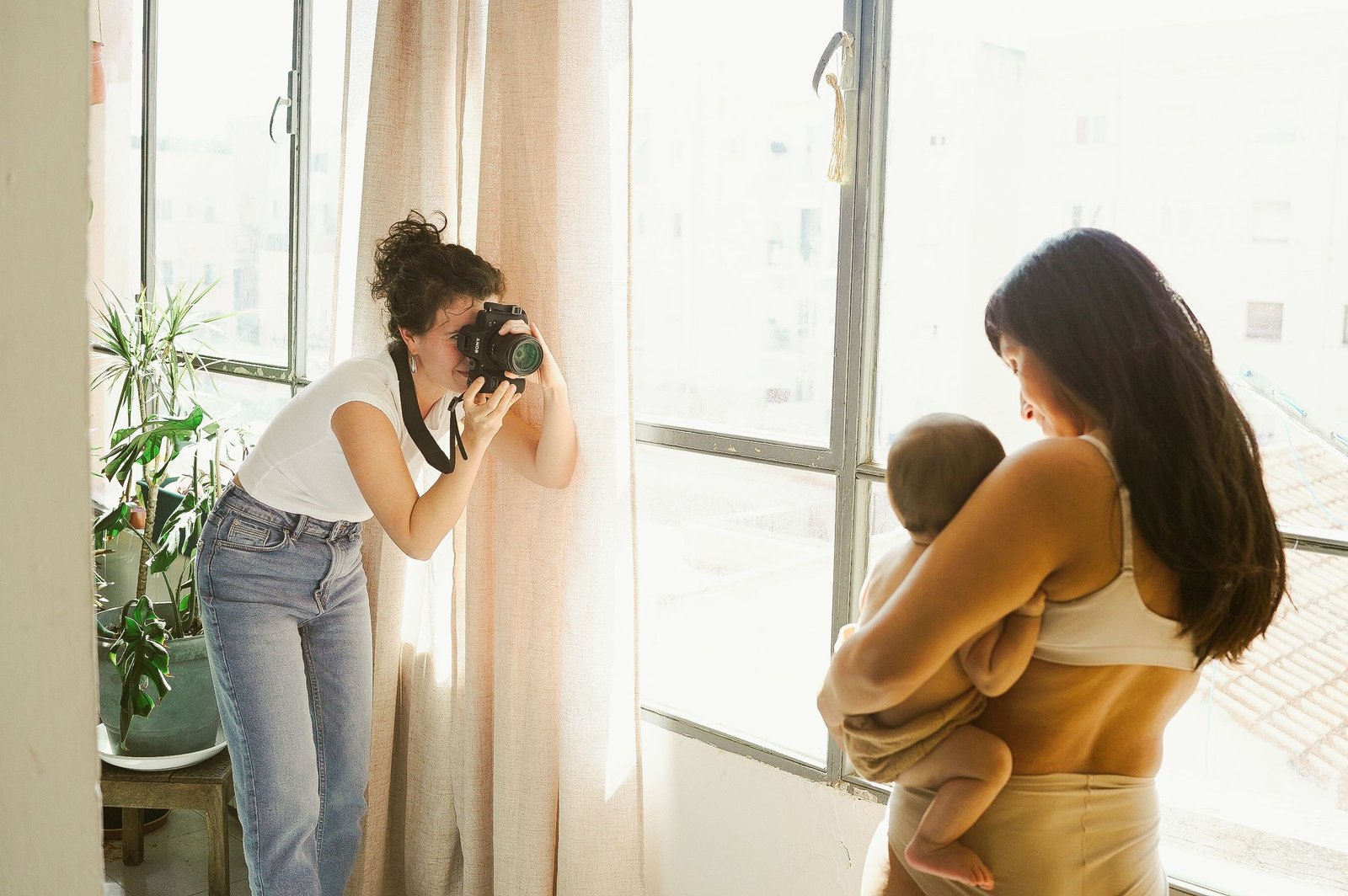 Laura fotografiando a una madre con su bebé junto a la ventana