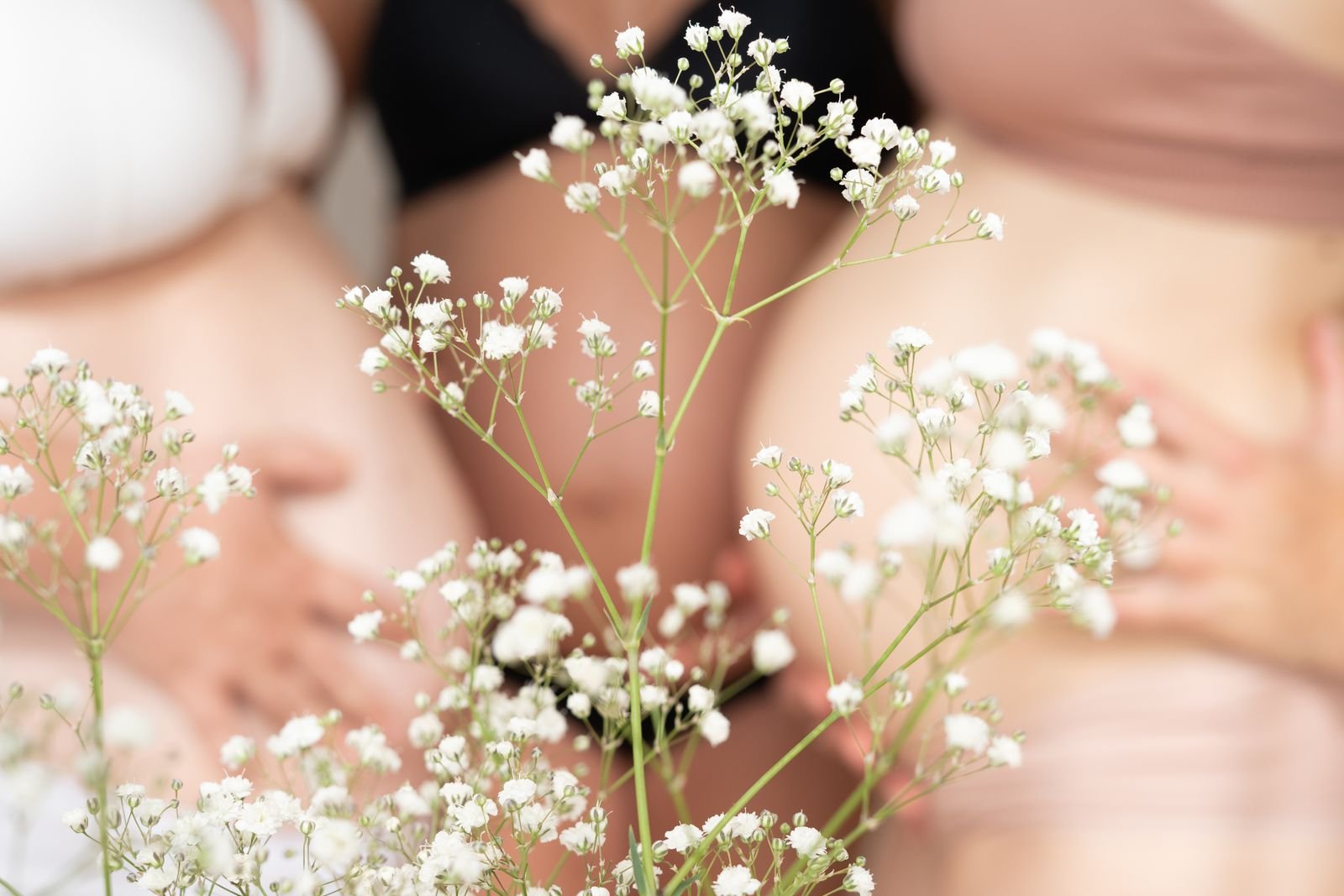 Manos sobre un vientre embarazado con flores blancas